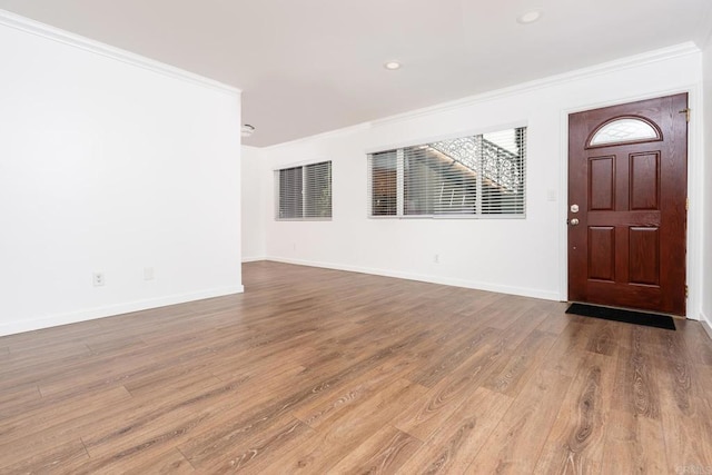 entryway with visible vents, crown molding, baseboards, and wood finished floors