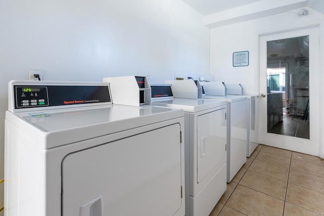 shared laundry area with washer and dryer and light tile patterned flooring