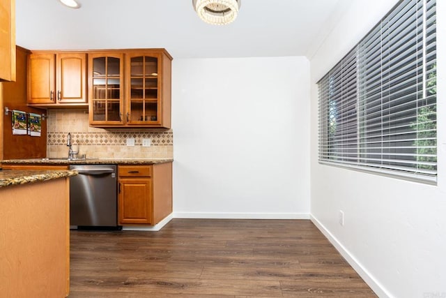 kitchen featuring tasteful backsplash, dishwasher, glass insert cabinets, dark wood-style flooring, and stone counters