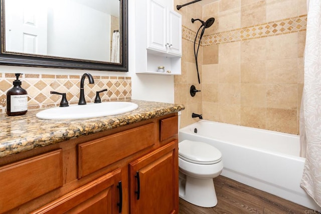 bathroom with toilet, wood finished floors, vanity, tasteful backsplash, and shower / bath combo