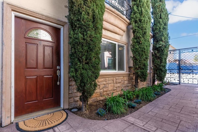 entrance to property with stone siding and fence