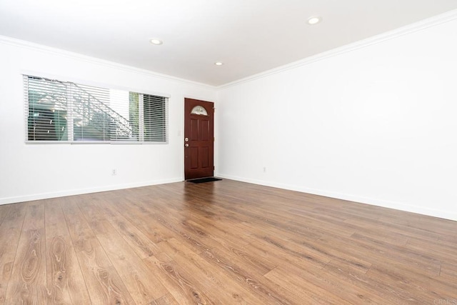 spare room featuring baseboards, recessed lighting, wood finished floors, and crown molding