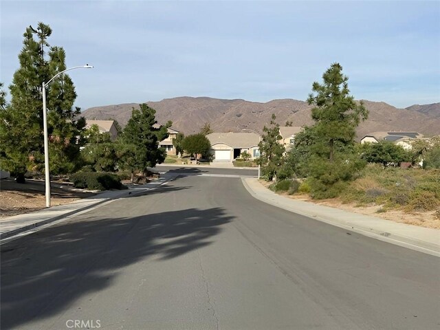 view of road featuring street lights, a mountain view, curbs, and sidewalks