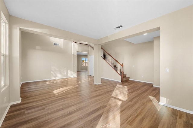 spare room featuring light wood-style floors, visible vents, stairway, and baseboards