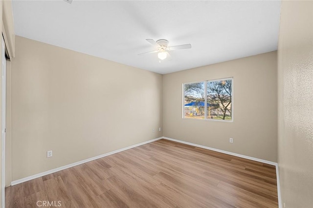 spare room featuring ceiling fan, baseboards, and wood finished floors