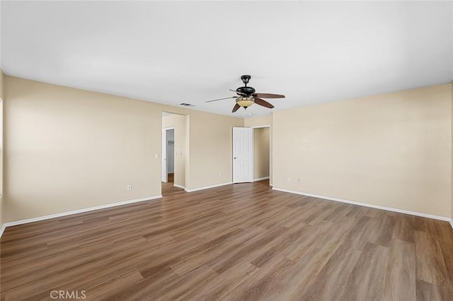 unfurnished room with ceiling fan, wood finished floors, visible vents, and baseboards