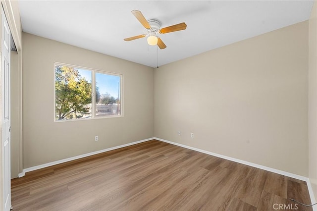 empty room featuring light wood-type flooring, baseboards, and a ceiling fan