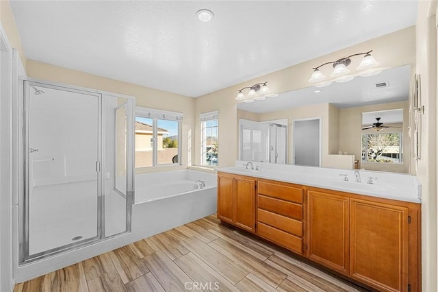 full bathroom featuring a bath, a shower stall, double vanity, and a sink