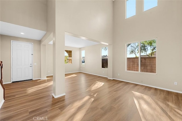 entryway with a high ceiling, baseboards, and wood finished floors