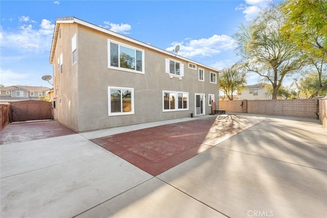 rear view of house featuring a patio, fence private yard, a gate, and stucco siding