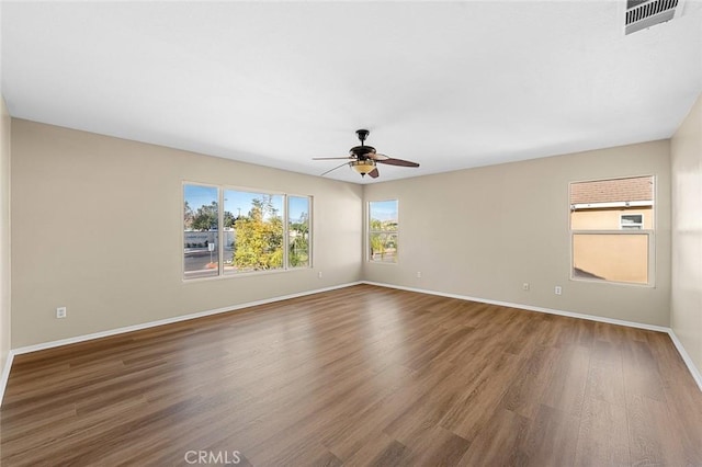 unfurnished room featuring ceiling fan, wood finished floors, visible vents, and baseboards