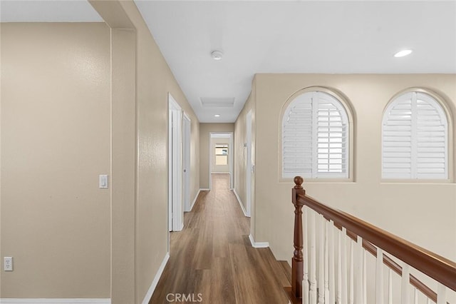 hall with baseboards, plenty of natural light, an upstairs landing, and wood finished floors