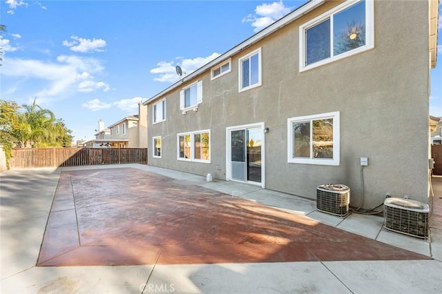 rear view of house featuring a patio area, fence, central AC, and stucco siding