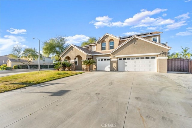 view of front facade featuring stucco siding, concrete driveway, a gate, roof mounted solar panels, and a garage