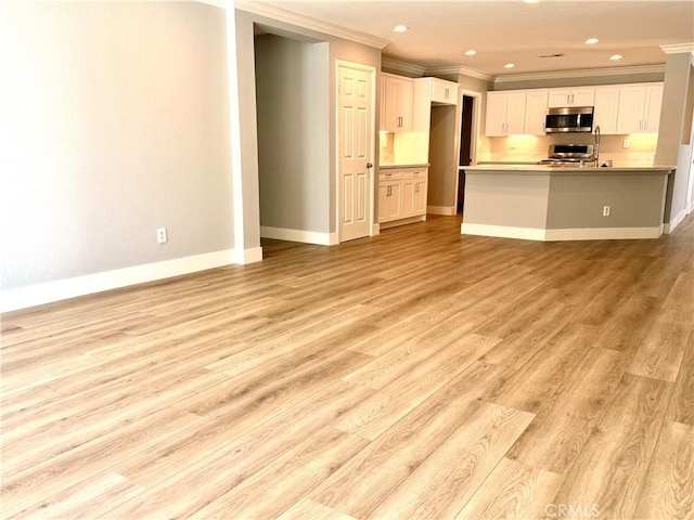 kitchen with open floor plan, stainless steel microwave, light wood finished floors, and baseboards