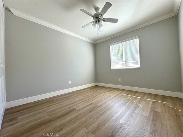 empty room with baseboards, ceiling fan, wood finished floors, and crown molding