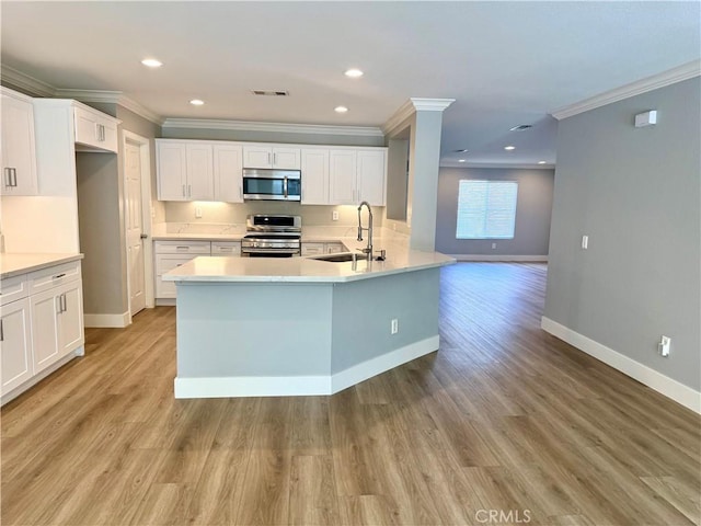 kitchen with stainless steel appliances, a sink, visible vents, baseboards, and light wood-type flooring