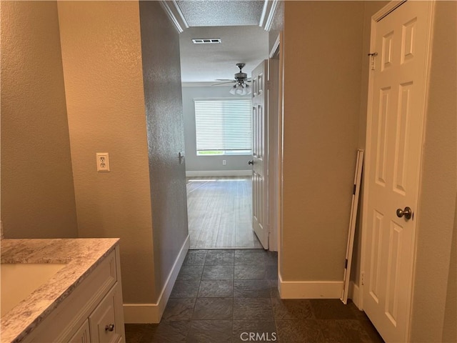 hall with visible vents, a sink, and baseboards