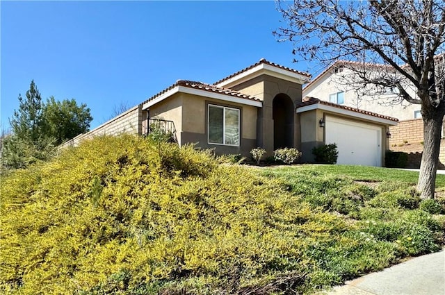 mediterranean / spanish-style home featuring a garage, a tiled roof, and stucco siding