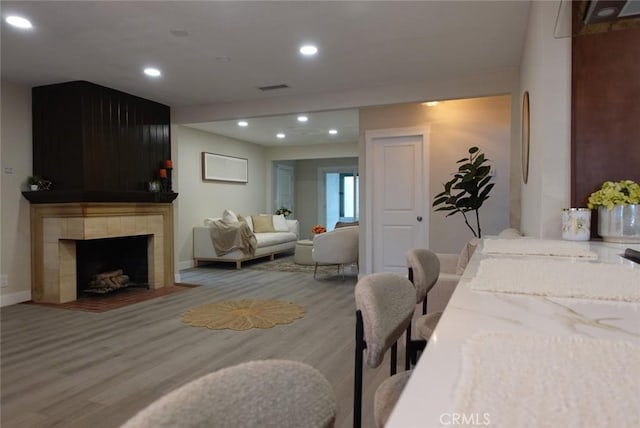 interior space featuring baseboards, visible vents, a tiled fireplace, wood finished floors, and recessed lighting