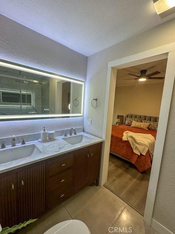 ensuite bathroom with a textured ceiling, a textured wall, a sink, and a shower stall