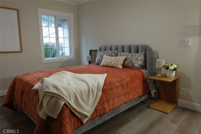 bedroom with crown molding, baseboards, and wood finished floors