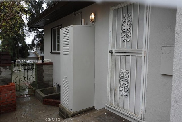 view of exterior entry with fence and stucco siding