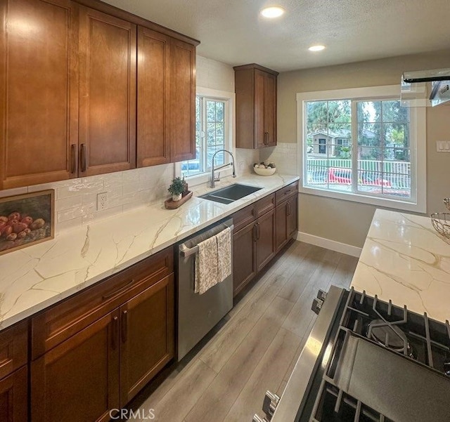 kitchen with tasteful backsplash, light wood-style flooring, a sink, light stone countertops, and dishwasher