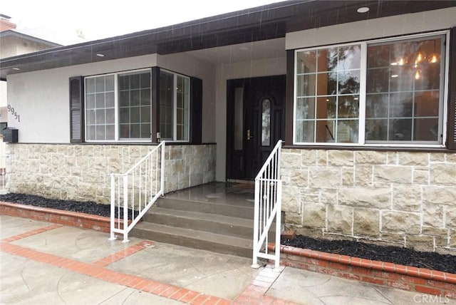 doorway to property featuring stone siding and stucco siding