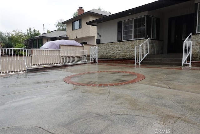 exterior space with a patio, a chimney, stone siding, and stucco siding