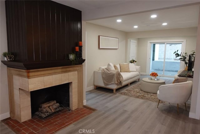 living area with light wood-type flooring, a fireplace, baseboards, and recessed lighting