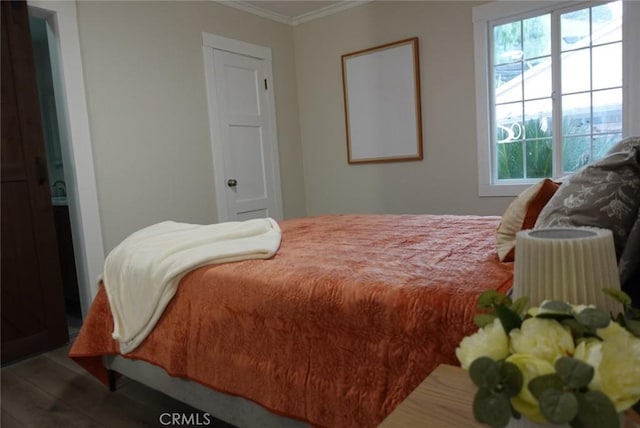 bedroom featuring ornamental molding and wood finished floors