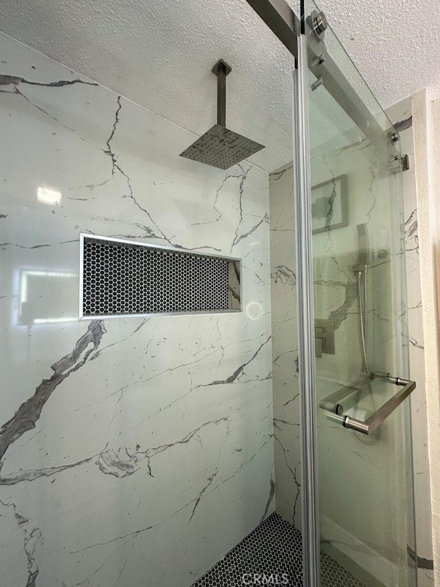 full bathroom with a marble finish shower and a textured ceiling