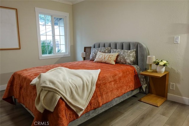 bedroom featuring ornamental molding, wood finished floors, and baseboards