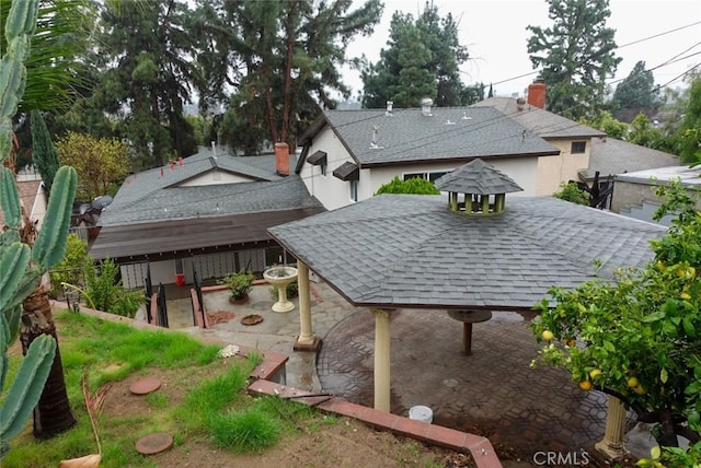 exterior space with roof with shingles and a patio area