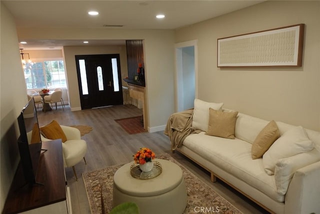 living room with a notable chandelier, recessed lighting, visible vents, wood finished floors, and baseboards