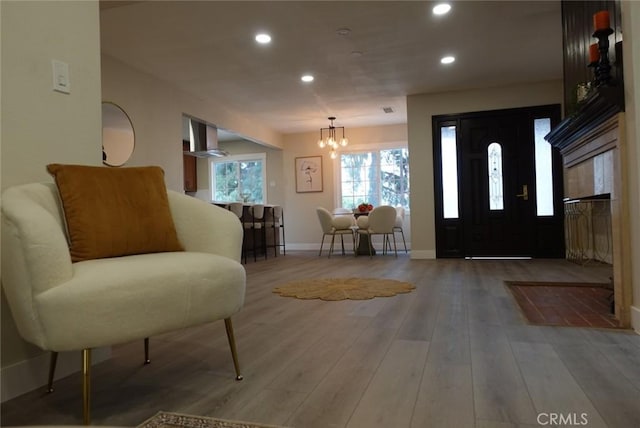 foyer with baseboards, an inviting chandelier, hardwood / wood-style flooring, and recessed lighting