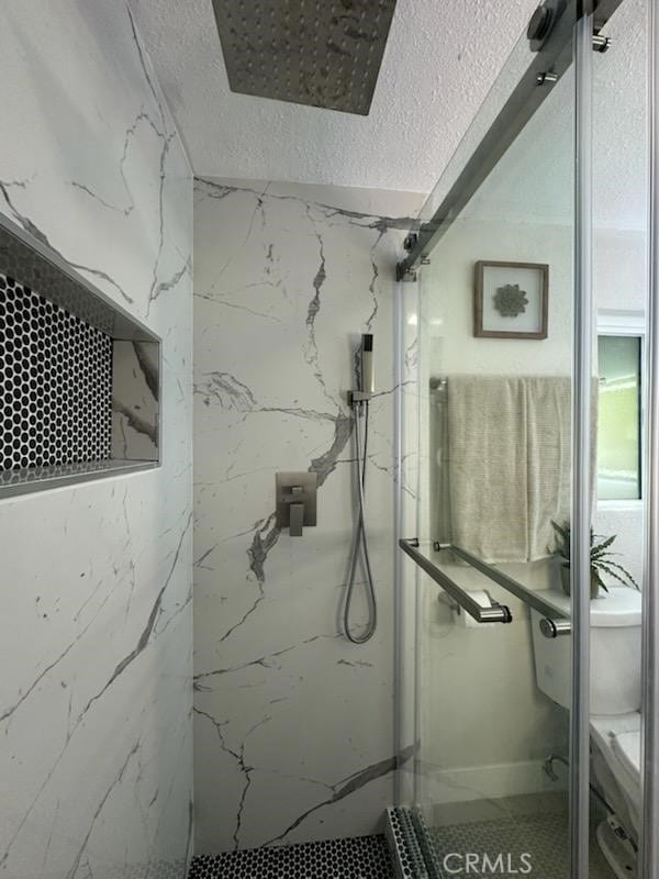 full bathroom featuring toilet, a textured ceiling, and a marble finish shower