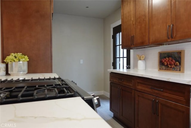 kitchen with baseboards, decorative backsplash, and light stone countertops