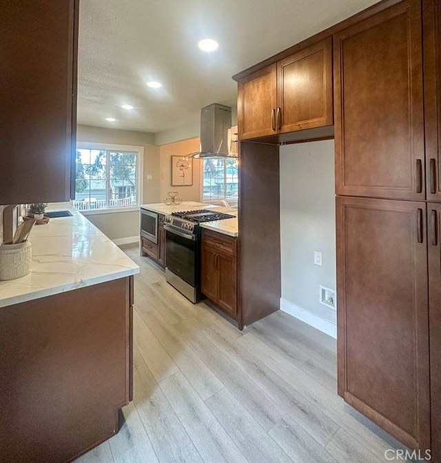 kitchen with light wood finished floors, baseboards, island range hood, and stainless steel appliances