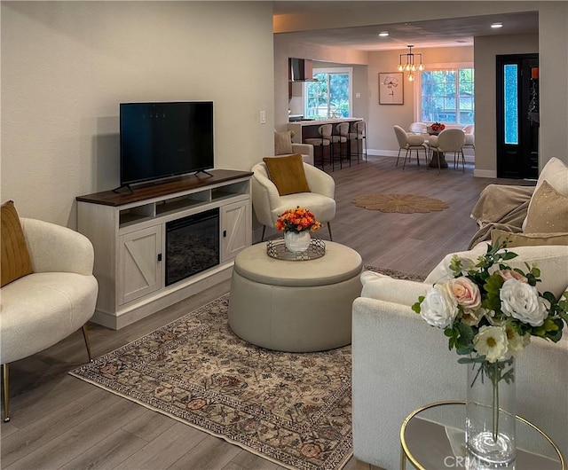 living room with a notable chandelier, recessed lighting, wood finished floors, and baseboards