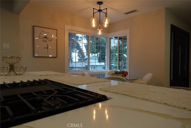 kitchen featuring light stone countertops, visible vents, stovetop, and decorative light fixtures