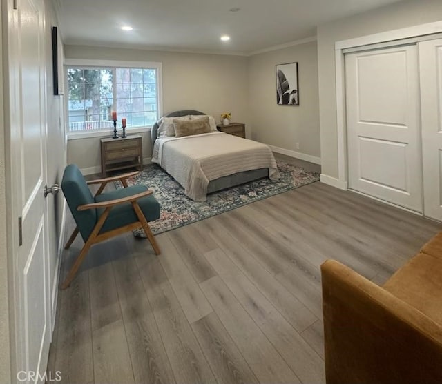 bedroom with baseboards, wood finished floors, crown molding, a closet, and recessed lighting