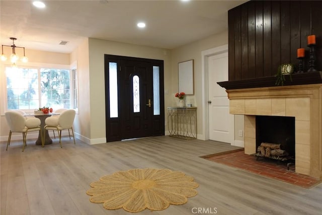 entrance foyer with recessed lighting, visible vents, light wood-style floors, a tile fireplace, and baseboards