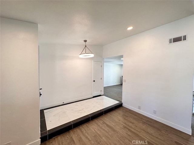 empty room with recessed lighting, visible vents, baseboards, and wood finished floors