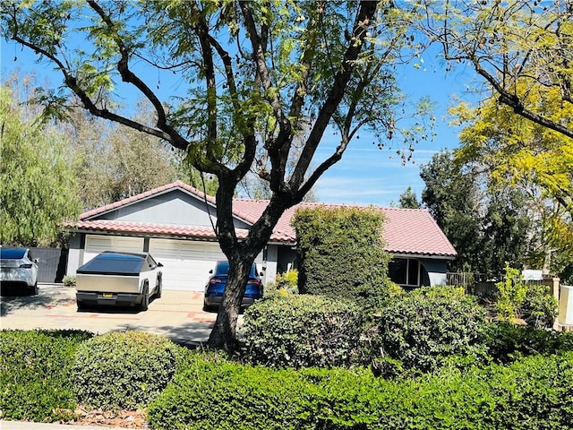 ranch-style house featuring driveway, a tile roof, fence, and an attached garage