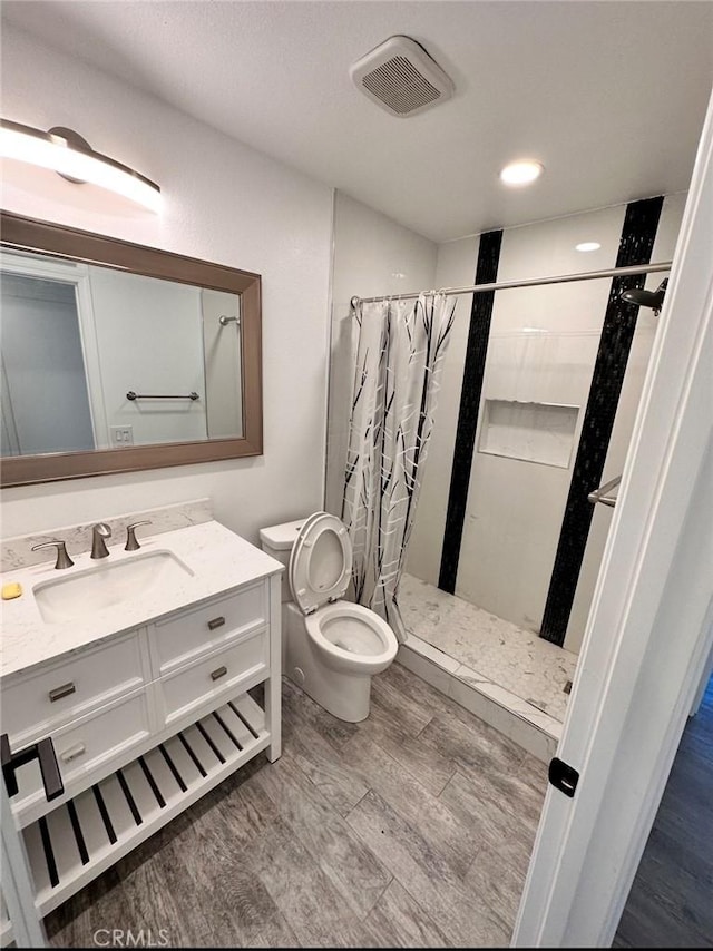 full bath featuring visible vents, toilet, a shower stall, vanity, and wood finished floors