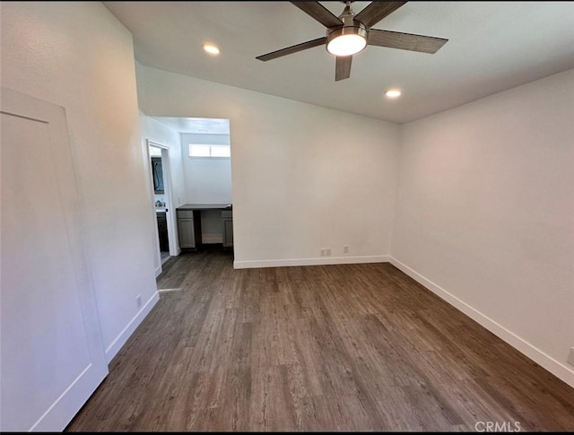 spare room with a ceiling fan, dark wood finished floors, and baseboards