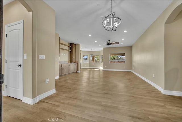 unfurnished living room featuring light wood-type flooring, arched walkways, baseboards, and recessed lighting