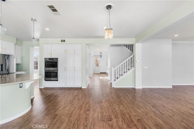 kitchen featuring stainless steel appliances, wood finished floors, visible vents, white cabinets, and open floor plan